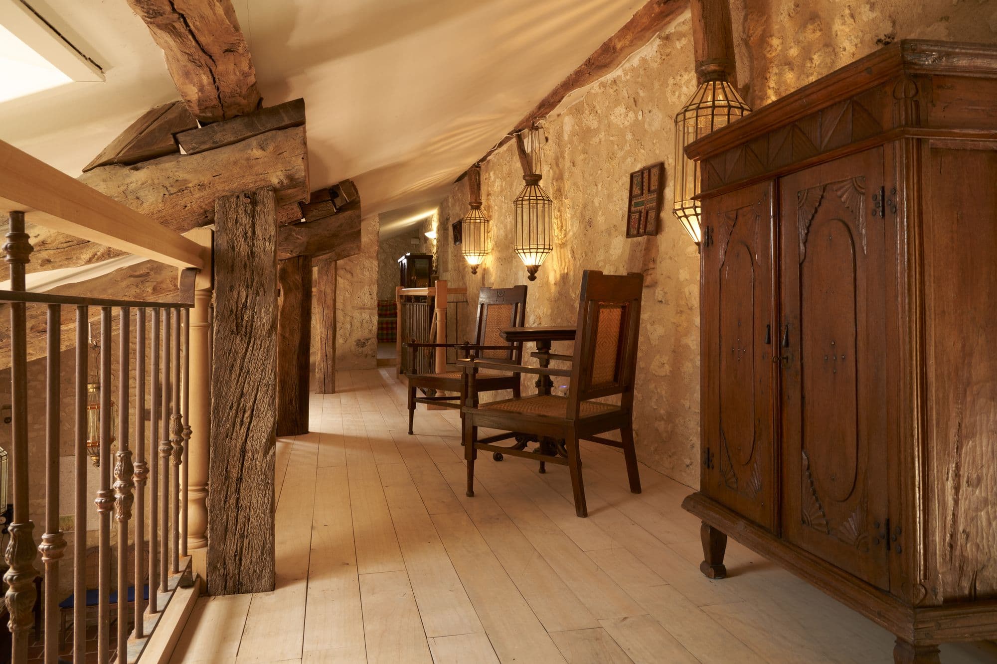 The upstairs landing with timber posts, an armoire and a table with chairs