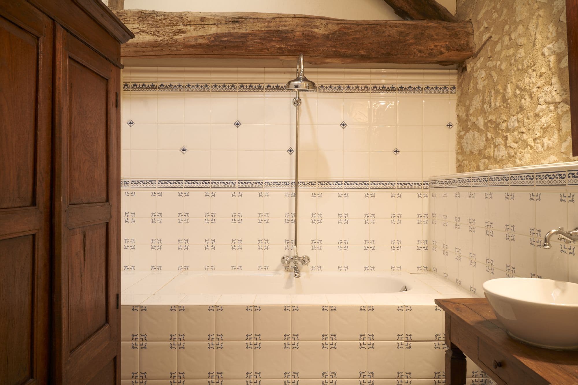 A bathroom with a bath and shower, a vessel basin and wooden panelling