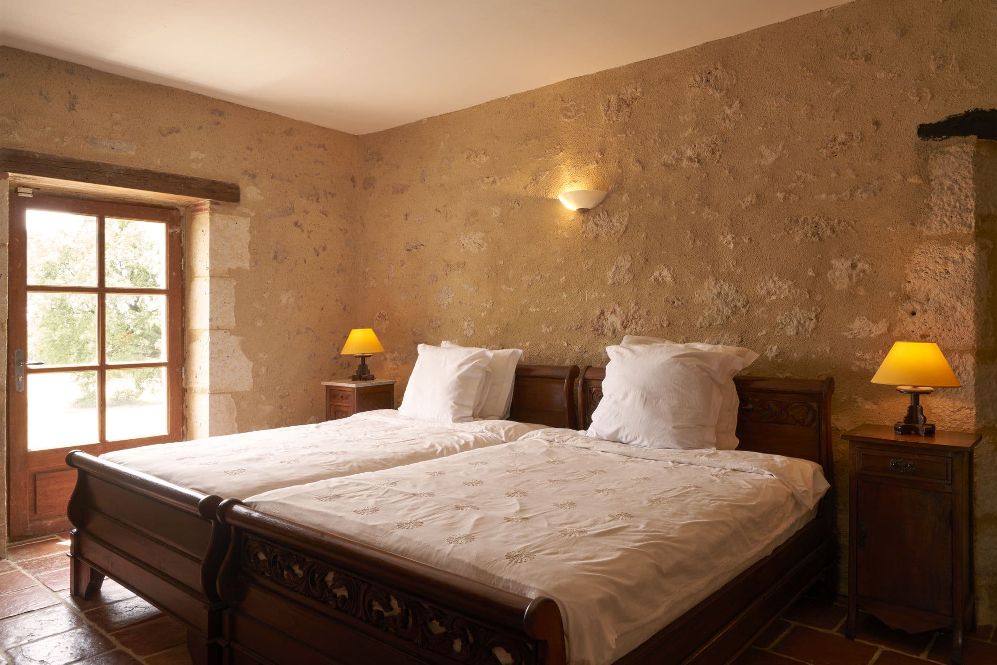 A bedroom with two carved sleigh beds beneath a window