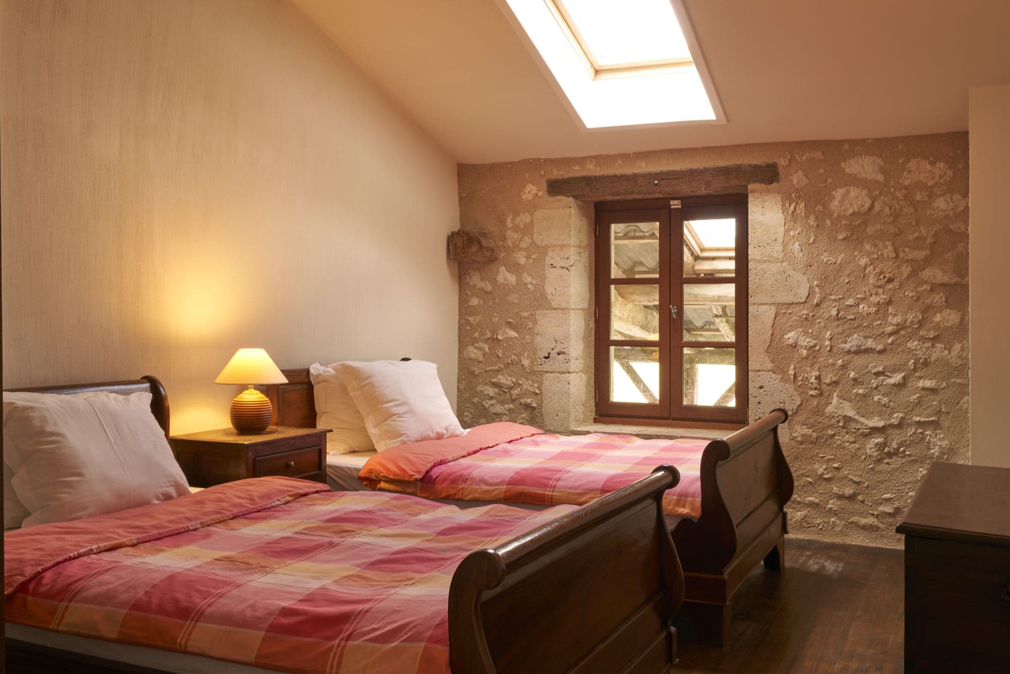 A bedroom under the roof with two twin sleigh beds and a skylight