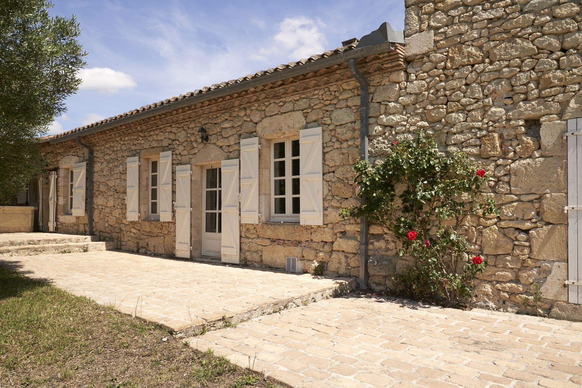 The stone facade of En Bosc with roses climbing it