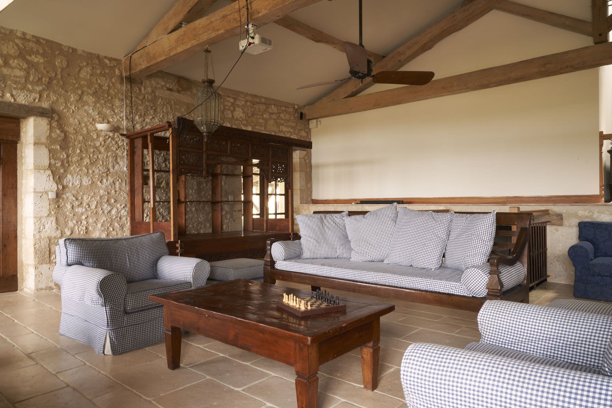 The living room under open timber trusses, furnished with carved Balinese mahogany