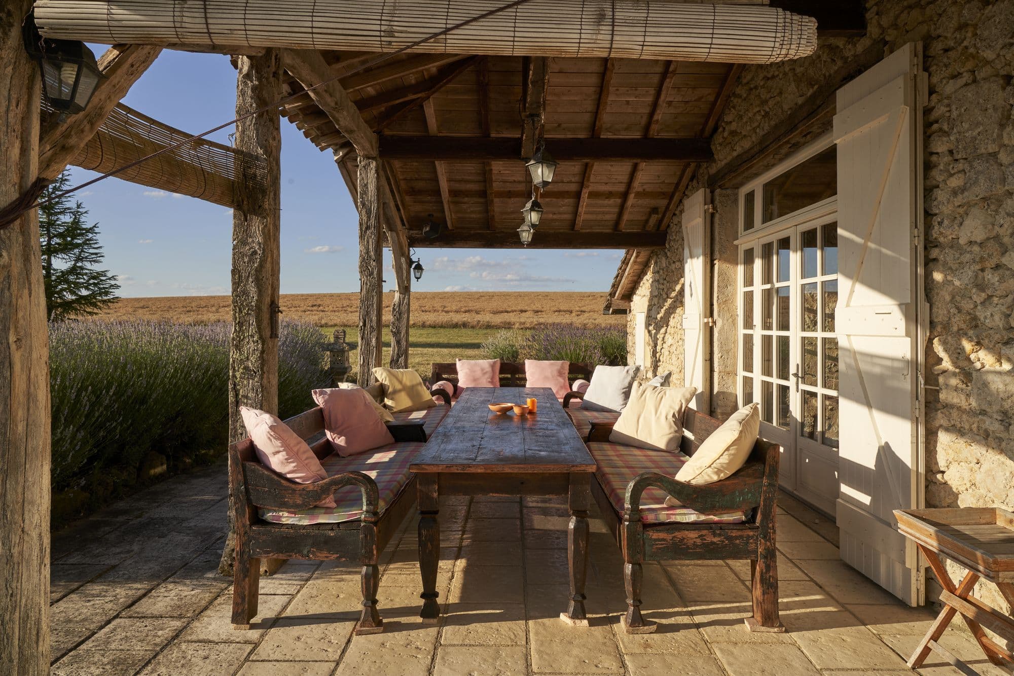 The covered terrace with a long table, looking out over lavender and wheat fields