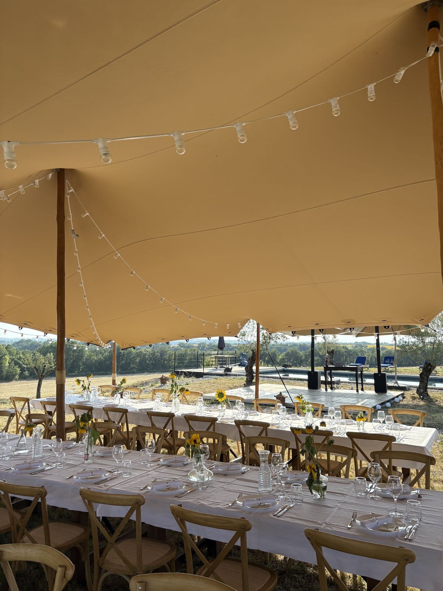 Tables laid inside the marquee, glassware and festoon lights